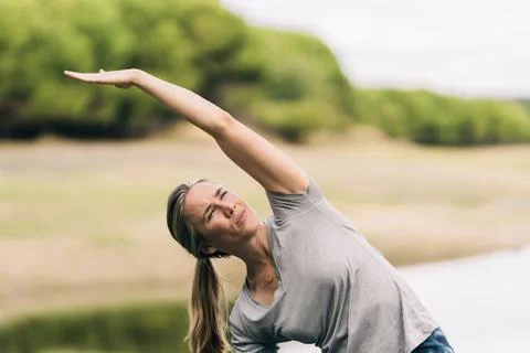 Female stretching her back while doing yoga in a park Stock Photos