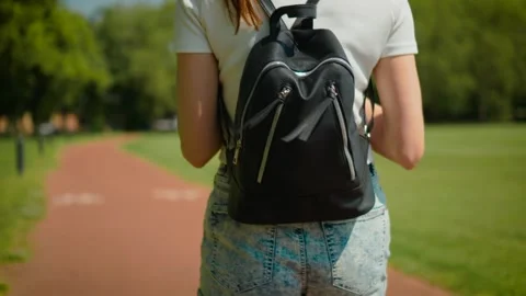 Female student carrying leather backpack while walking through athletics stadium Stock Footage 338069466