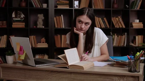 Female student does homework using laptop and textbooks Stock Footage 300385814