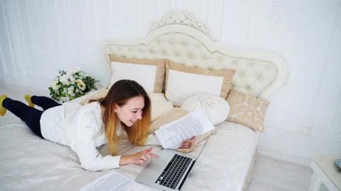 Female Student Doing Homework on Computer and Reads Information on Papers Lying Stock Photos