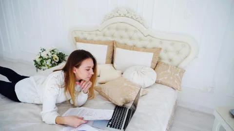 Female Student Doing Homework on Computer and Reads Information on Papers Lying Stock Photos