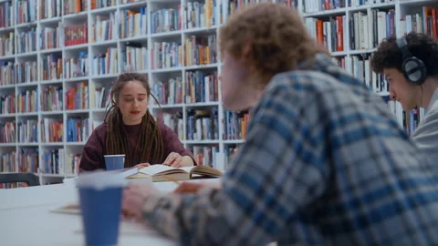 Female student with dreadlocks reading a book in a library Stock Footage 335125505