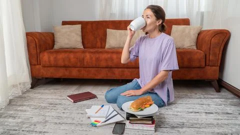 Female student drinks coffee while studying at home Stock Photos