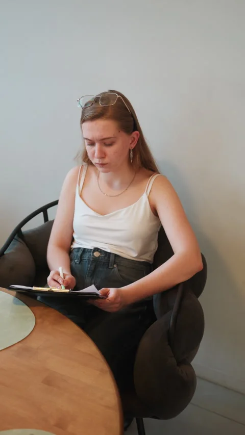 Female student engaged in writing during study session indoors. Female Stock Footage 335543341
