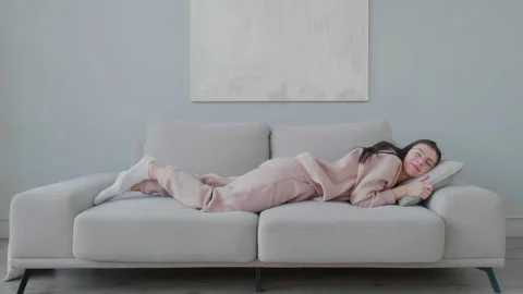 Female student getting sleep on sofa to rest in living room, daytime. Stock Footage 149142827