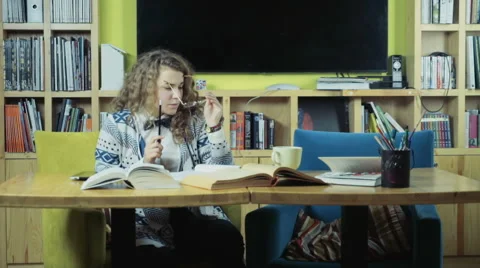 Female student gnawing a pencil while reading books slow motion Stock Footage 59186512