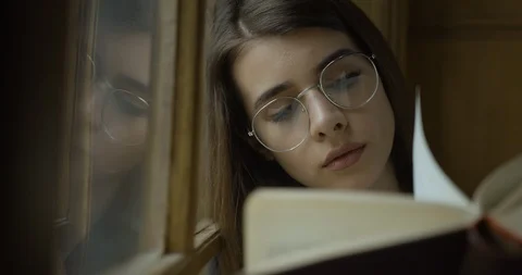 Female student, library. Pretty young female student reads a book Stock Footage 101978412