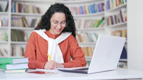 Female student listens to online e-learning, video course in campus library  Stock Footage 247855879