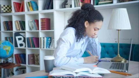 Female student making a note while preparing for exams in university library 스톡 사진