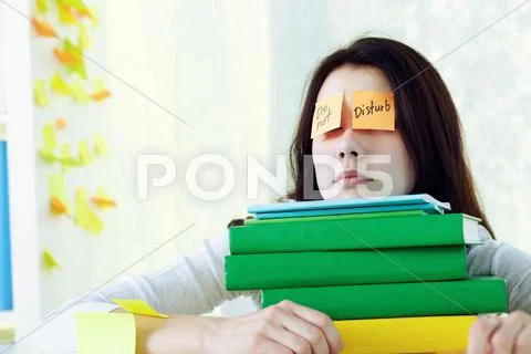 Female student napping on stack of textbooks Stock Photos