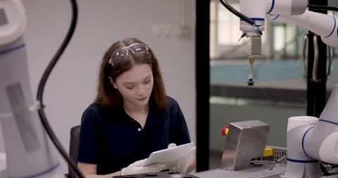 Female student operating robotic arm using tablet while observing object Stock Footage 316075828