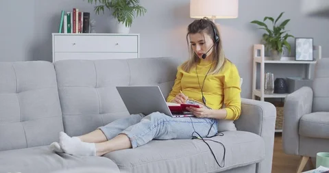 Female student processing a new topic with online tutor, listening through Stock Footage 129932714