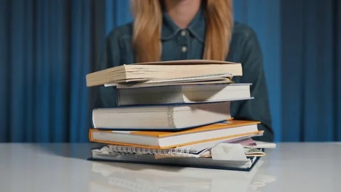 A female student rejects a stack of books and selects a tablet. A lot of work Video stock 82358893
