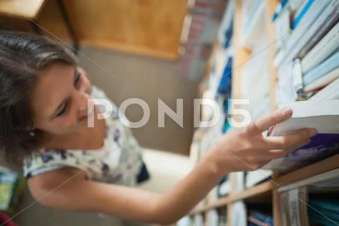 Female student selecting book in the library Stock Photos