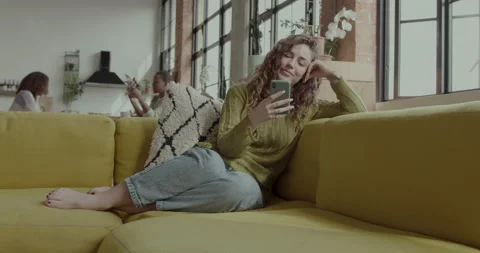 Female Student on Sofa looking at Smart phone in Warehouse conversion Stock Footage 237741220