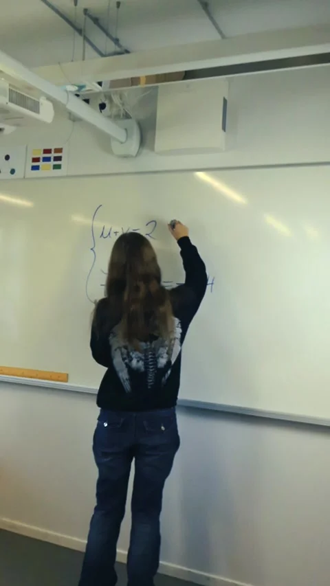Female student solving complex math equation on a whiteboard Vidéo 345550812