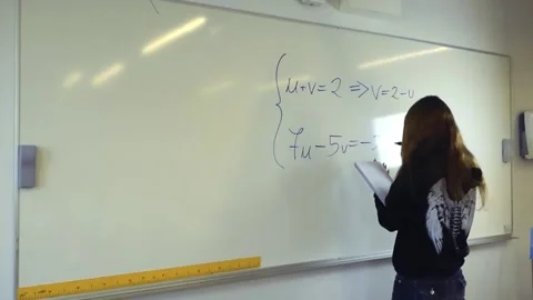 Female student solving a math problem on a classroom whiteboard Stockbeeldmateriaal 345188598