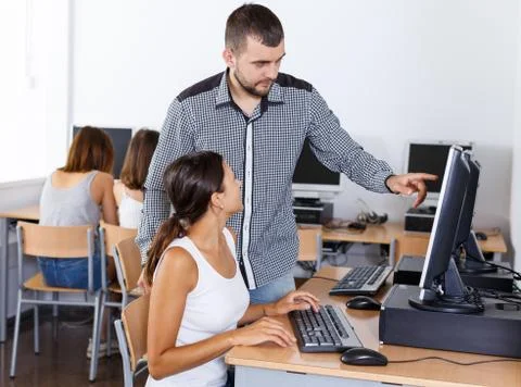 Female student studying in computing class with teacher Fotos Stock