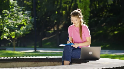 Female student studying outside using laptop Video stock 181831139