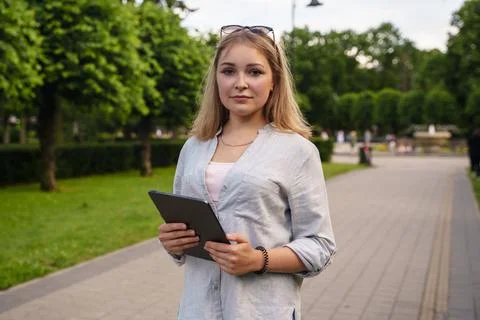 Female student with tablet looking at camera in summer park Stock Photos