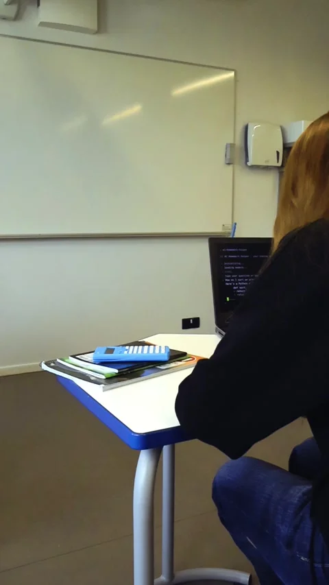 Female student using an AI chatbot for homework in a classroom Stock Footage 347575888