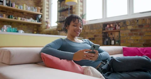 Female Student using Smartphone to check home finances on Sofa Stock Footage 297256596