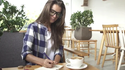 Female student working writing notes in local study hangout cafe. Stock Footage 77611493
