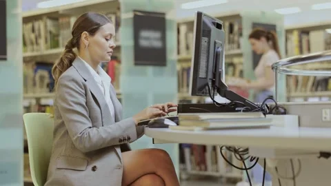 Female student works at computer in library Stock Footage 329396082