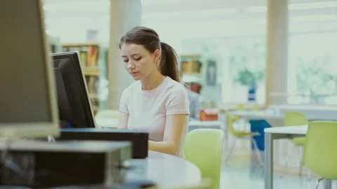 Female student works at computer in library Stock Footage 332637372