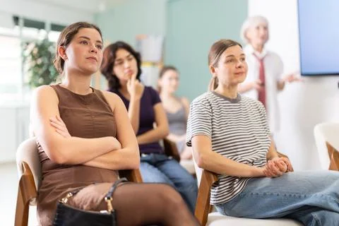 Female students are sitting in study room. Coach speaker telling in background. Stock Photos
