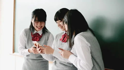 Female students talking while looking at smartphone in front of blackboard Stock Footage 161891861