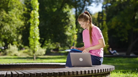 Female students using laptop for studying in park Stock Footage 164227175
