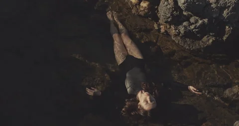 Female surfer lying down on rocks near ocean. Filmed on cinematic camera, 12 bit Stock Footage 143893784