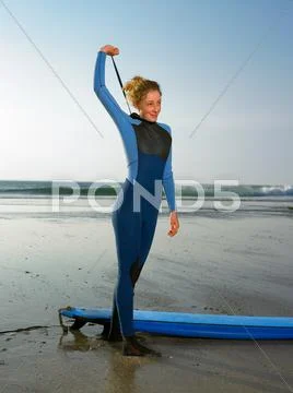Female Surfer Standing On A Beach