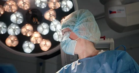 Female surgeon focused during complex medical procedure in bright operating room Stock Footage 302717796