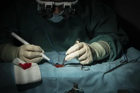 Female surgeon performs a micro-surgery operation on one arm. Stock Photos