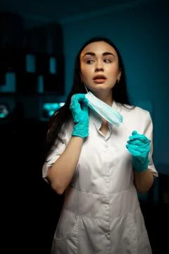 Female surgeon posing while removing face mask Stock Photos