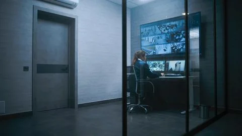Female surveillance operator controls security cameras in monitoring center Foto stock