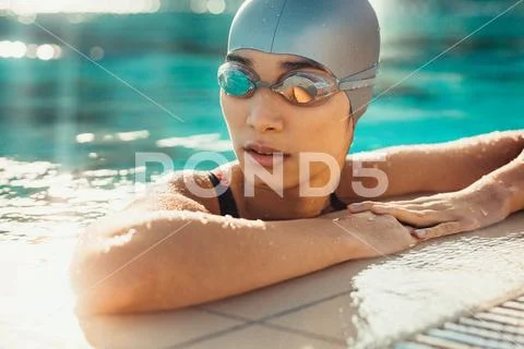 Female swimmer relaxing at the edge of a swimming pool Stock Photos