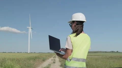 Female system engineer in helmet with notebook near wind power generator Stock Footage 301420832