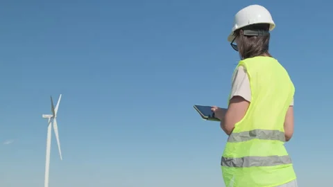 Female system engineer in helmet with tablet near wind power generator Vidéo 301420802