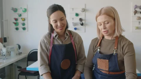 Female Tailor and Young Apprentice Choosing Leather in Workshop Stock Footage 244680664