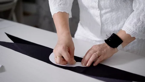 Female tailor making pattern on tissue by pinning paper pattern. Stock Footage 77542618