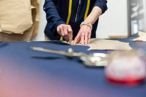 Female tailor marking fabric with pattern in menswear workshop Stock Photos