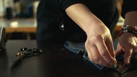 A female tailor marking hem on a pair of old vintage jeans Stock Footage 221239347