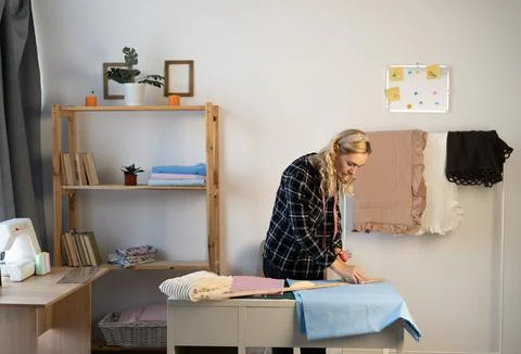 Female tailor measuring of fabric for pattern cutting in workshop. Professional Stock Photos