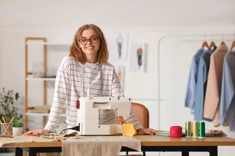 Female tailor with sewing machine at table in atelier Stock Photos
