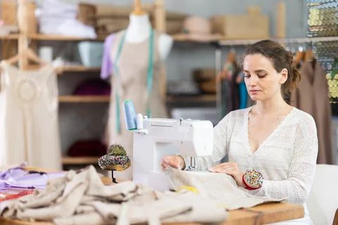 Female tailor using sewing machine to make garment in studio Stock Photos