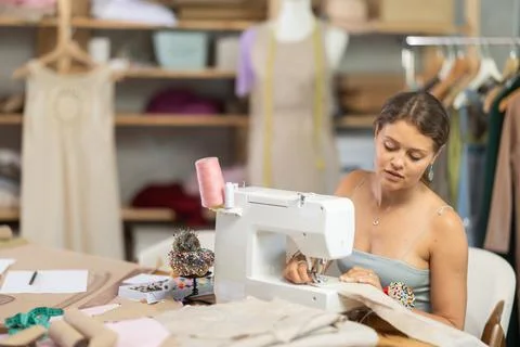 Female tailor using sewing machine to make garment in studio Stock Photos