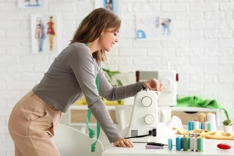 Female tailor using sewing machine on table in atelier Stock Photos